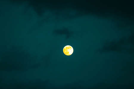 A scary yellow fool moon of a dark sky with clouds, mystical night background.