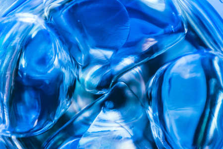 Abstract blue background, liquid drink with ice in a glass. Drinking fresh water concept.の写真素材