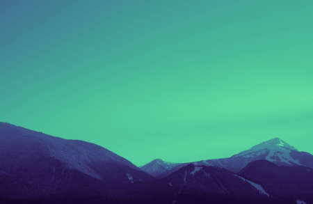 Photo depicting a beautiful moody frosty landscape. Colorful European alpine mountains with snow peaks on a sky background.の写真素材