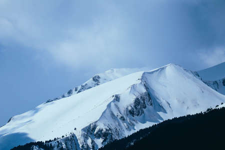 Mountain snow peak, beautiful natural winter backdrop. Ice top of the hill, blue sky background. Alpine landscape.の写真素材
