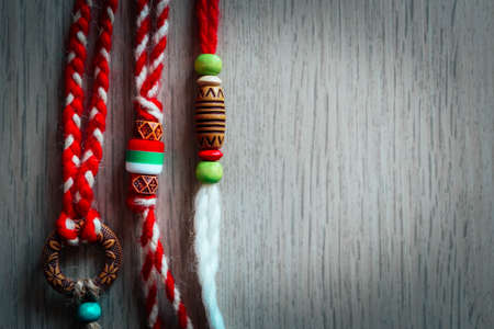 Bulgarian traditional spring decor martenitsa bracelets, wooden background. Baba Marta holiday,...