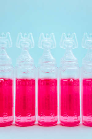 Abstract medical background, an ampoules with pink liquid. Vaccine in bottles background.