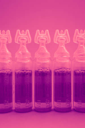 Abstract medical background, an ampoules with pink liquid. Vaccine in bottles background.