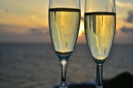 Two glasses of white wine with sunset on backgroundの写真素材