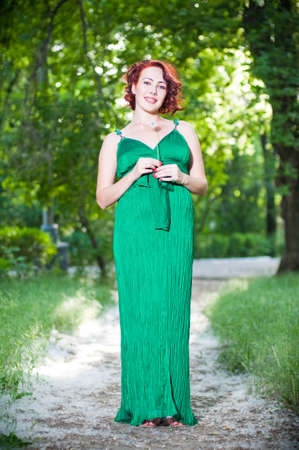 Young pregnant woman in a green dress in the gardenの写真素材