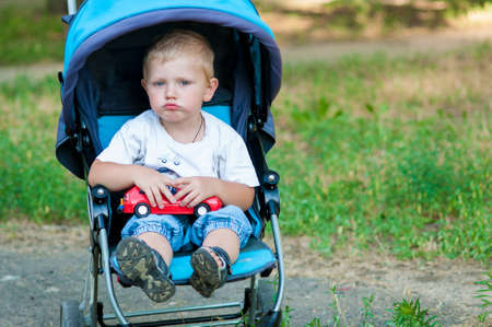Little boy in a pram on a walk in the parkの写真素材