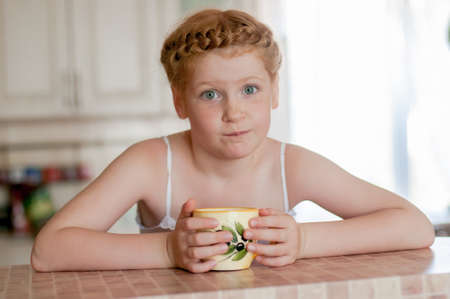   Little girl c cup of tea in the kitchenの写真素材