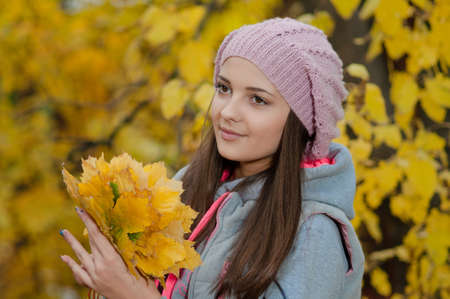 Young girl in a park in autumn with yellow leavesの写真素材
