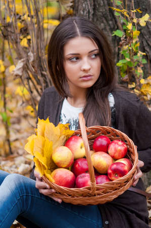 Young girl in autumn park with a basket of applesの写真素材