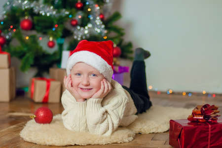 little boy in santa hat near Christmas tree with giftsの写真素材
