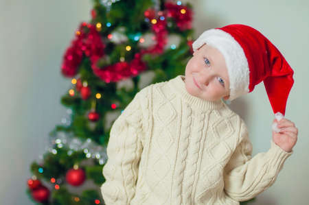 little boy in santa hat near Christmas tree with giftsの写真素材