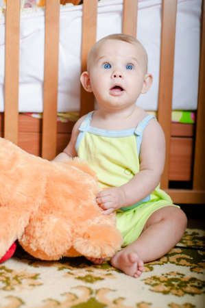 Infant baby playing on the floor at home with teddy bearの写真素材