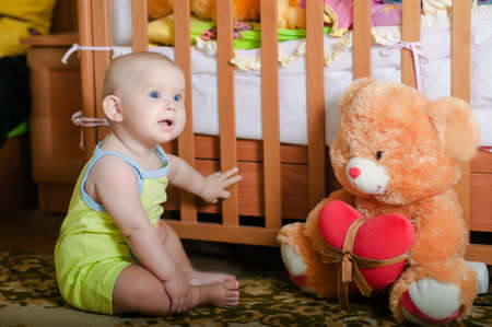 Infant baby playing on the floor at home with teddy bearの写真素材