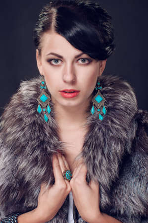 Young woman in a fur coat in beautiful earringsの写真素材