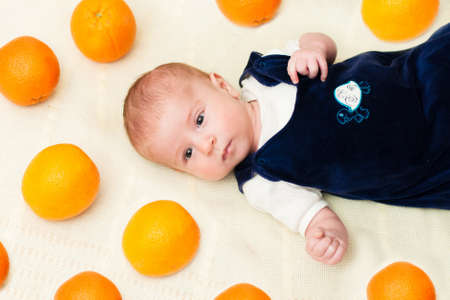 baby lying on the bed with orangesの写真素材