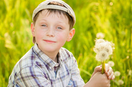 Boy on summer nature with dandelions smillingの写真素材