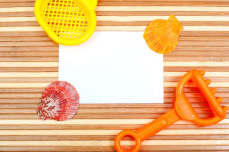Paper card and seashells toy shovel on wooden backgroundの写真素材