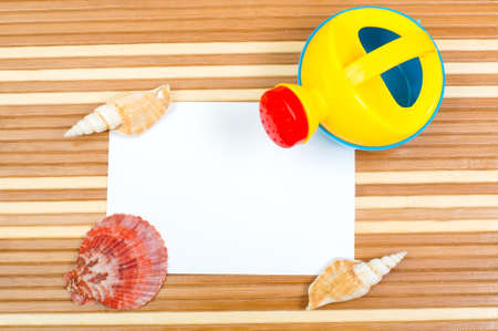 Paper card and seashells toy shovel on wooden backgroundの写真素材