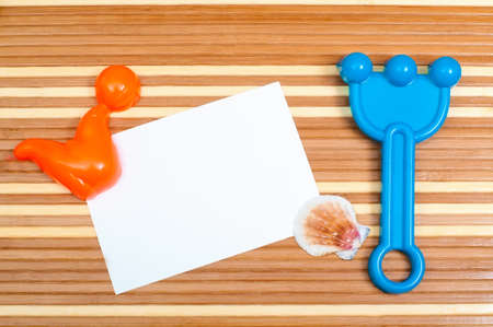 Paper card and seashells toy shovel on wooden backgroundの写真素材