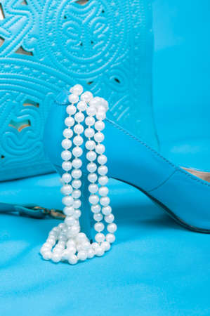 Beautiful blue shoes and handbag, pearls on blue background