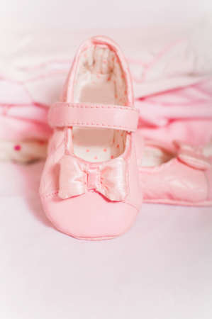 Little pink baby shoes and baby clothesの写真素材