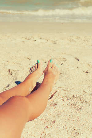 Girl feet in the sand on the beach in summerの写真素材