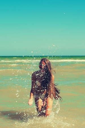 Young girl in the sea water splashes and smiling summerの写真素材