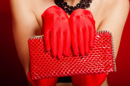Female hands in red gloves holding a red clutch bagの写真素材