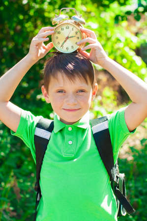 boy with a backpack and a clock in hands on nature