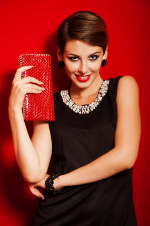 Beautiful girl with a red clutch bag in her handsの写真素材