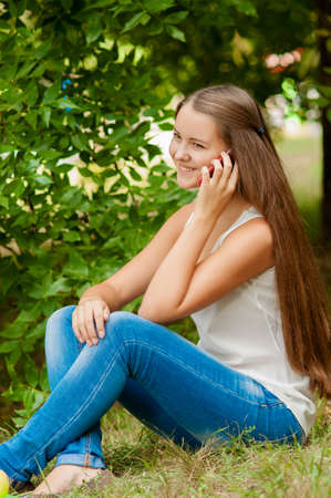 Teenage girl with a mobile phone near a treeの写真素材