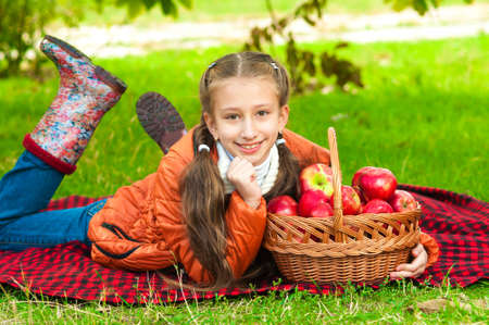 Little girl with apples in autumn parkの写真素材