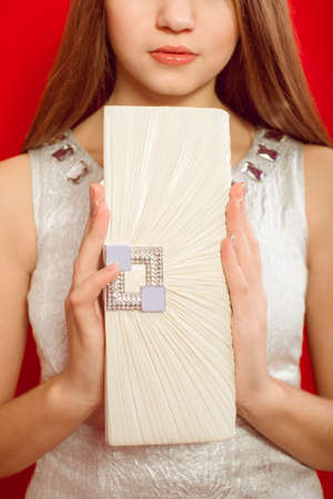 Beautiful girl with long hair in a trendy dress and white clutchの写真素材