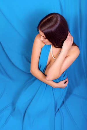 Beautiful young girl with long hair in a long blue dress and jeweleryの写真素材