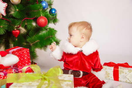 Baby in Santa costume at the Christmas tree with giftsの写真素材