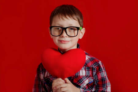 Little boy in glasses with a heart of toy in handsの写真素材