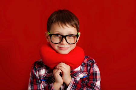Little boy in glasses with a heart of toy in handsの写真素材