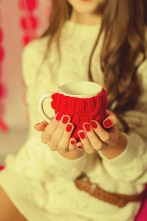 Beautiful girl with a cup of tea on a pink background