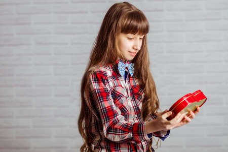 Little girl with a red box of chocolates in a heart shapeの写真素材