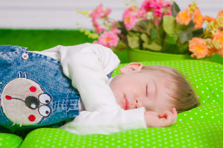 Little baby sleeping on a green cushionの写真素材
