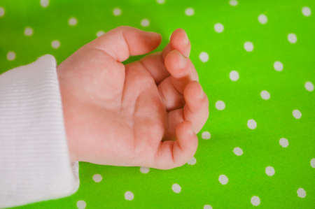 Hand of a little baby sleeping on a green cushionの写真素材