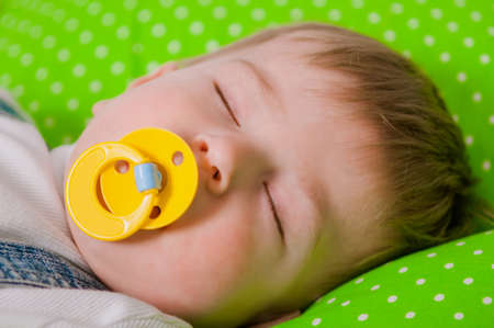 Little baby sleeping on a green cushionの写真素材