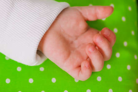 Hand of a little baby sleeping on a green cushionの写真素材