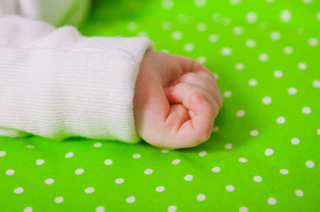 Hand of a little baby sleeping on a green cushionの写真素材