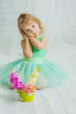 Little girl in beautiful dress with spring flowers in a vaseの写真素材