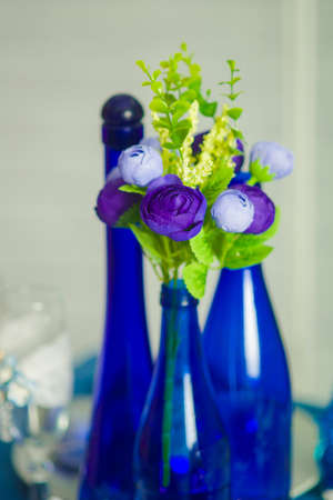 Bridal bouquet of blue iris white tulips glasses and bottles of blueの写真素材