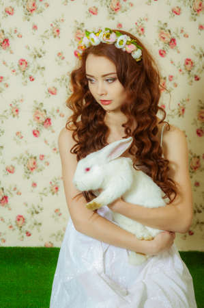 Young girl with long hair in a flower wreath with white rabbitの写真素材