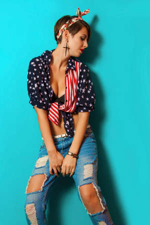 Beautiful girl in jeans and a shirt on a blue backgroundの写真素材