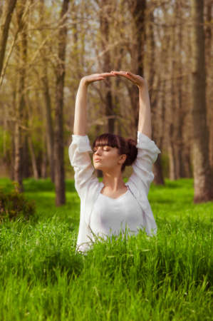 Young girl doing yoga on a green grass in summer