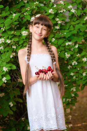 Little girl with summer cherries in her handsの写真素材